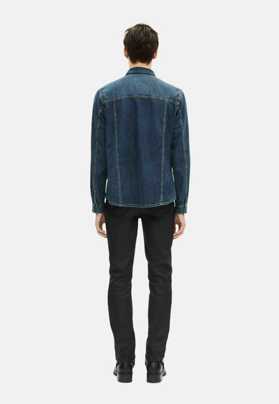 Ciemnoniebieska kurtka dżinsowa z klasycznym kołnierzykiem, zapinana na guziki z przodu, o prostym kroju. Połączona z czarnymi spodniami typu slim fit i czarnymi butami.