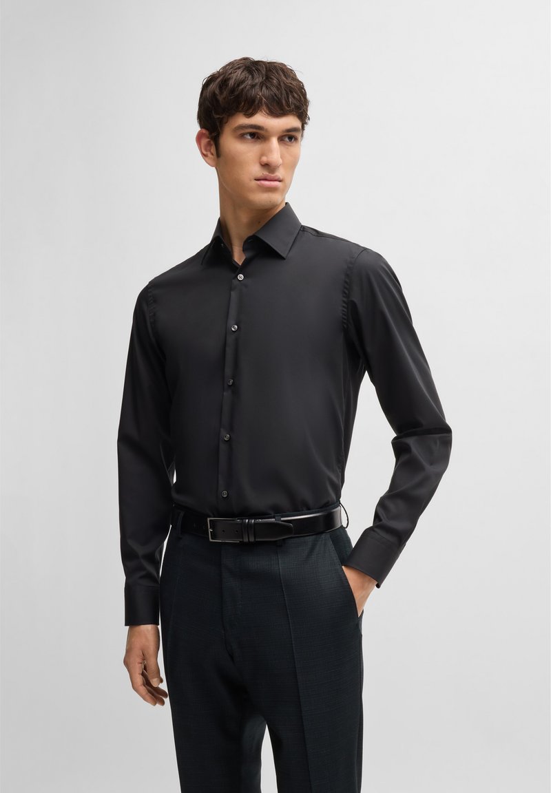 Black dress shirt with a pointed collar, slim fit, long sleeves, and button closure. Smooth fabric with a subtle sheen.