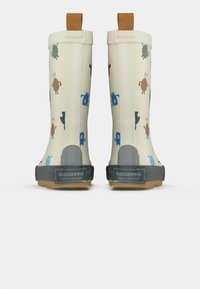 Bottes de pluie off-white pour enfants avec des motifs colorés de monstres de dessin animé, semelles grises et tirants marron vus de l'arrière.