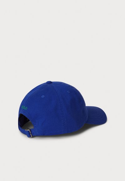 Boné de beisebol em algodão azul com aba curva, correia ajustável e bordado verde "POLO" na parte de trás. Textura macia, design casual.