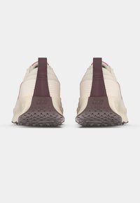 Αθλητικά παπούτσια σε ανοιχτό μπεζ και σκούρο μαρόν χρώμα με υφασμάτινη υφή, έντονη στήριξη στη φτέρνα και λαστιχένια σόλα με μοτίβο πρόσφυσης.