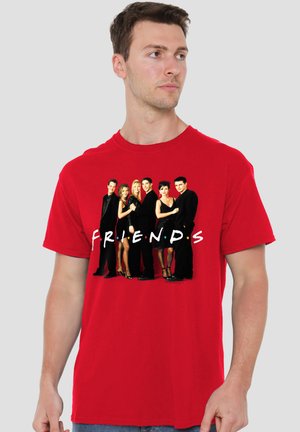 Man wearing red t-shirt with a group photo of six people dressed in black and the word "FRIENDS" in white letters across the chest.