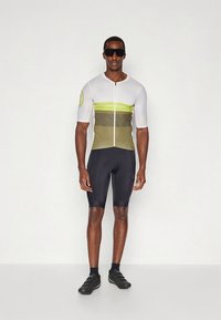 Jalgrattasõidu särgi valget ja oliivrohelist värvi, rohelise triibuga, lühikeste varrukatega, esiküljel lukuga; sobitatud mustade lühikeste pükste ja jalgrattajalatsitega.