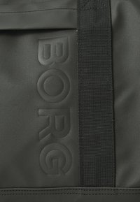 Sac textile noir avec logo "BORG" en relief, présentant une surface texturée et une bandoulière noire résistante pour une durabilité accrue.