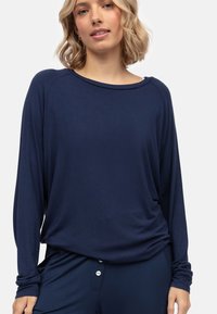 Marineblauw langemouwen top gemaakt van zachte stof. Heeft een brede halslijn, een losse pasvorm en geplooide details bij de taille voor extra drape.