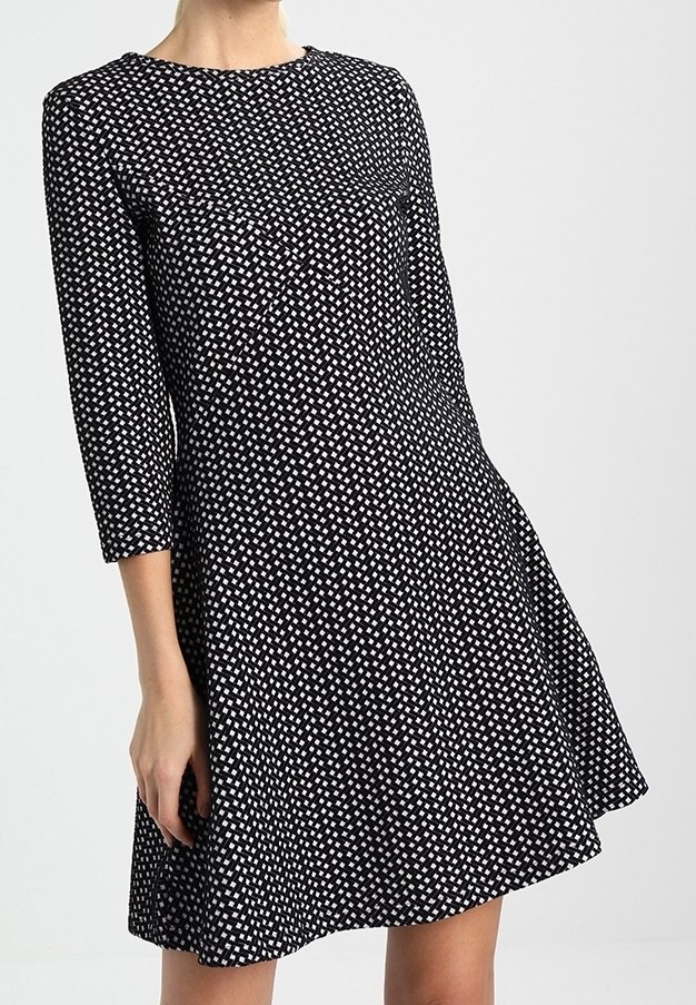 Robe noire à manches trois-quarts, ornée d'un motif géométrique blanc, avec un col rond et une silhouette évasée. Texture de tissu lisse.