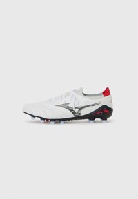 Witte voetbalschoenen met een gestructureerde bovenkant met diagonale strepen, zwarte accenten en een rode hiel; plastic noppen voor grip.
