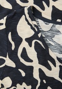 Schwarz-weißes abstraktes Stoffmuster mit sichtbaren Nähten und einem V-förmigen Nahtdetail.