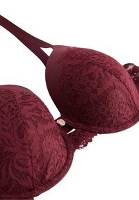 Burgundy pitsivä lace-rintaliivit kukkakuviolla, pehmeät kupit, ohuet hihnat ja pieni koristeellinen vaaleanpunainen ruusu keskellä etuosaa.