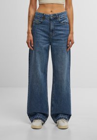 Wide-leg, high-waisted blue denim jeans with a classic five-pocket design. Features visible stitching and a faded finish.