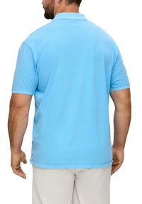 Lichtblauw polo shirt van zacht katoen, met korte mouwen, een klassieke kraag en subtiele textuurdetails, gedragen door een persoon die van de camera af staat.