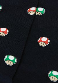 Tejido de punto azul marino con iconos de champiñones impresos dispersos en rojo y verde, cada uno con rasgos faciales distintos y manchas blancas.