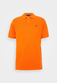 Pomarańczowa bawełniana koszulka polo z dwoma guzikami, krótkimi rękawami i małym niebieskim logo na lewej piersi. Jednolity kolor, klasyczny design.