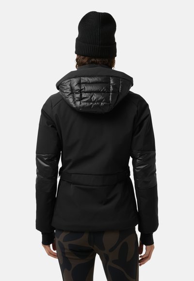 Zwarte geïsoleerde jas met een gewatteerde capuchon, een ceintuur in de taille en contrasterende glanzende mouwen. Draagt bijpassende leggings met patroon. De textuur lijkt glad.