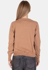 Maglione marrone con maniche lunghe, colletto a girocollo rigato e orlo elasticizzato, abbinato a jeans grigi. Texture liscia, design casual.