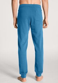 Blauwe katoenen sweatpants met een rekbare tailleband en verplichte enkels. Voorzien van een achterzakdetail. Glad textuur, casual pasvorm.