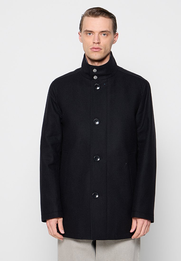 Manteau en laine noir avec un col haut, six boutons sur le devant et des poches latérales. Le design est droit avec une texture lisse.