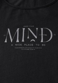T-shirt en coton noir avec texte imprimé blanc : "FAITES DE VOTRE ESPRIT UN ENDROIT AGRÉABLE." Le texte est usé et comprend un élément graphique dans la lettre "D."