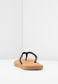 Mustat letitetut vyö sandaalit beige kumipohjalla, jossa on tasainen muotoilu ja sileä pinta. Minimalistinen tyyli, ilman huomattavia yksityiskohtia.