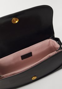 Borsa in pelle nera con finitura liscia, chiusura a scatto dorata e fodera in raso rosa; presenta un'etichetta con marchio all'interno.