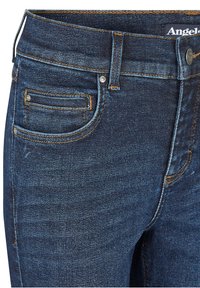 Dunkelblaue Jeans aus Denim mit glatter Textur, ausgestattet mit einer Vordertasche, kontrastierenden Nähten und einem Metallknopfverschluss.