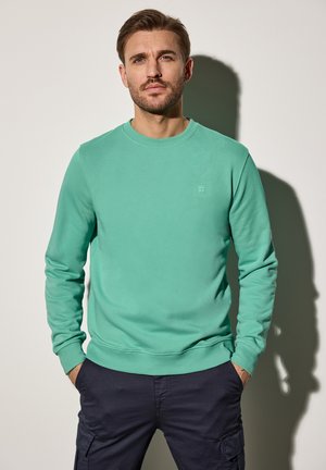 Muntgroene sweatshirt van katoen met een ronde hals en geribbelde manchetten, gecombineerd met marineblauwe cargobroek. Eenvoudige logo-details op de borst.