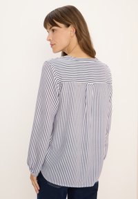 Camicia a maniche lunghe a righe con scollatura rotonda, caratterizzata da righe verticali blu e bianche e un dettaglio plissé sul retro per una maggiore texture.