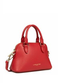 Sac à main en cuir rouge avec une texture granuleuse, doubles poignées, accents en métal doré et fermeture éclair. Logo de la marque affiché à l'avant.