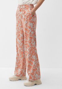 Pantaloni ampi e fluidi in tessuto corallo con un leggero motivo floreale azzurro. Presentano tasche laterali e un design a vita alta.