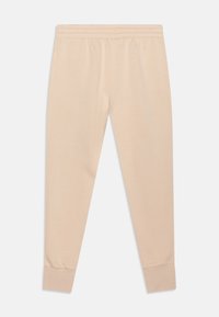 Světlé béžové tepláky s elastickým pasem a přiléhavými manžetami. Vyrobené z měkké tkaniny, s hladkou strukturou a bez viditelných vzorů.