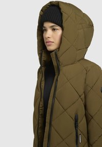 Quiltet olivengrøn pufferjakke med stor hætte, frontlynlås og to sidelommer. Har diamantformet quiltning for tekstur.