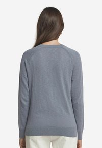 Ljusgrå tröja med långa ärmar, rund halsringning och ribbade muddar. Mjuk textur och något lös passform, har design med raglanärmar.