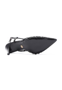 Zapato de tacón alto negro de punta afilada con acabado brillante, que presenta una correa de tobillo texturizada, tacón pequeño, suela plana y un branding sutil.