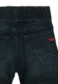 Jeans in denim scuro con cintura elasticizzata, due tasche posteriori e un piccolo dettaglio in cucitura rossa sulla tasca destra.