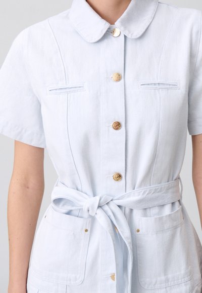 Robe en denim bleu clair avec une fermeture à boutons sur le devant, un col pointu, des manches courtes, une ceinture à nouer à la taille et deux poches avant avec des accents dorés.