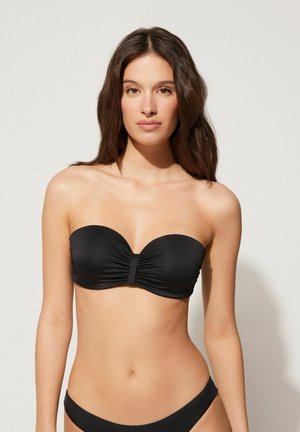 Czarny bikini bandeau z zebranym detalem na środku, gładką teksturą i bezszwowymi krawędziami. Dopasowane majtki charakteryzują się umiarkowanym zakryciem.