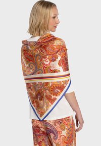 Écharpe en soie avec un motif cachemire rouge, orange et bleu, présentant une forme triangulaire et une bordure contrastée à rayures.