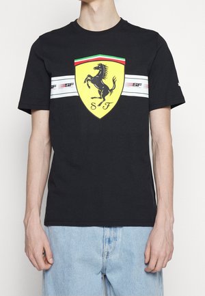 Černé bavlněné tričko s žlutým logem Ferrari a designem skákajícího koně. Obsahuje bílé horizontální pruhy s červenými a zelenými akcenty.
