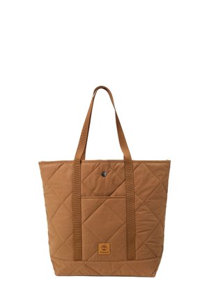 Sac cabas matelassé marron avec deux longues poignées, poche avant pressionnée et écusson logo Timberland sur fond blanc uni.
