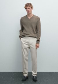 Brown, textured v-neck sweater paired with light beige trousers and black loafers. Simple, classic design with a relaxed fit.