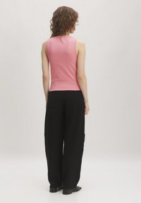 Roze mouwloze top van zachte stof, gecombineerd met losse zwarte broek met zakken en een wijd ontwerp.