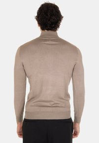Maglione beige a costine con maniche lunghe e colletto alto, caratterizzato da una silhouette aderente e una texture liscia, mostrato di spalle.