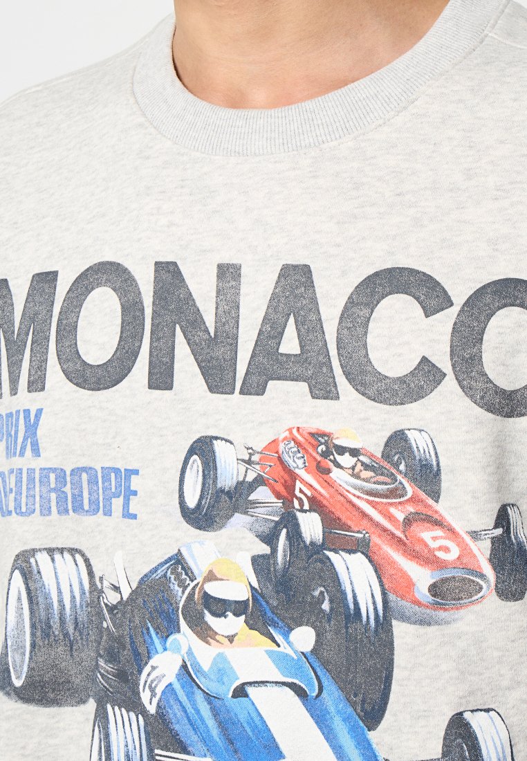 Heather-grauer Sweatshirt mit einem grafischen Druck von zwei Rennautos in Blau und Rot, begleitet von dem Text "MONACO" und "PRIX EUROPE" in fetter Schrift.