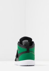 Høj top sneakers med en sort syntetisk overdel og grønne accenter, polstret krave, hvid sål og logo detalje på bagsiden.