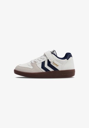 Witte en beige lage sneaker met navy accenten, klittenbandsluiting en bruine zool, gebrandmerkt met het "hummel" logo op de zijkant en zool.