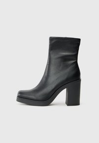 Schwarze Lederknöchelstiefel mit hohem Blockabsatz, glatter Textur, enganliegendem Design und genähten Details am oberen Rand.