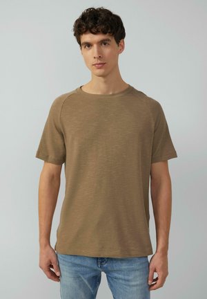 Braunes kurzärmliges T-Shirt mit feiner Textur, Rundhalsausschnitt und Raglanärmeln, kombiniert mit hellblauen Jeans.