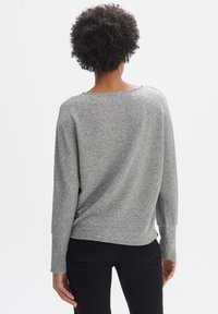 Maglione grigio a pullover con texture a coste e vestibilità oversized. Presenta maniche lunghe e un'ampia scollatura, progettato per il comfort e la facilità di indossarlo.