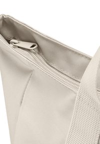 Zbliżenie na róg beżowej torby z materiału, ukazujące zamek błyskawiczny oraz szczegóły plecionego uchwytu.