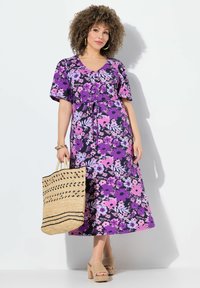 Květinové maxikabát v purpurové, růžové a černé barvě. Krátké rozšiřující se rukávy, v-výstřih, zavazování v pase, doplněno tkanou kabelkou a masivními sandály.